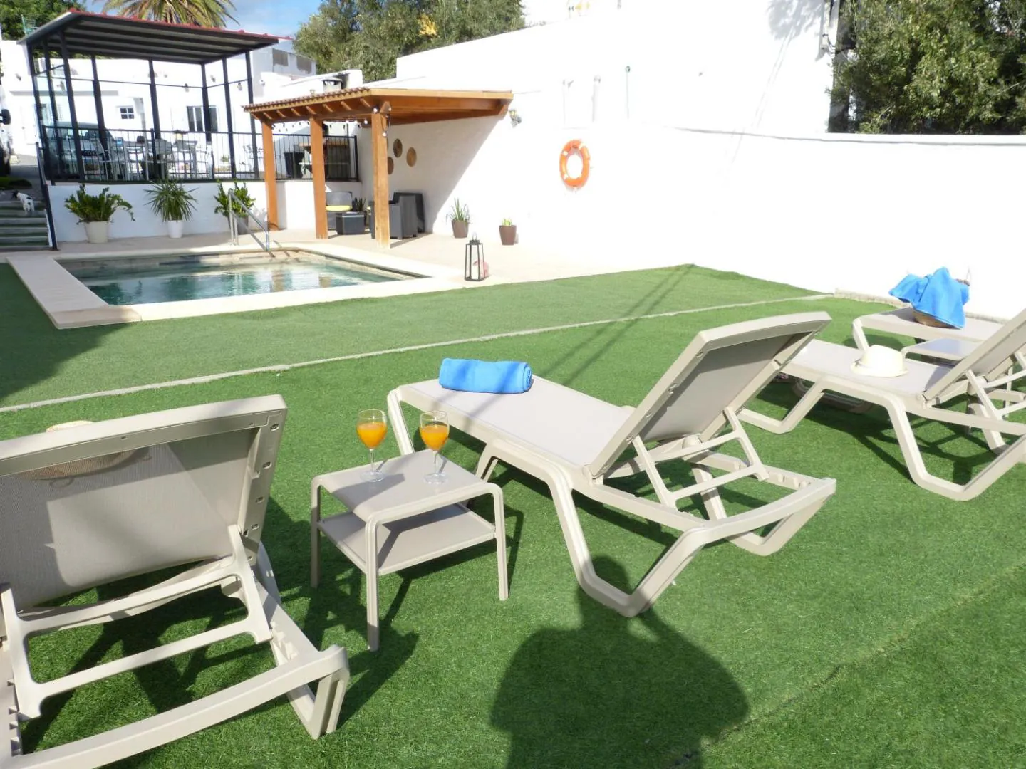 White loungers with towels on the lawn by the pool