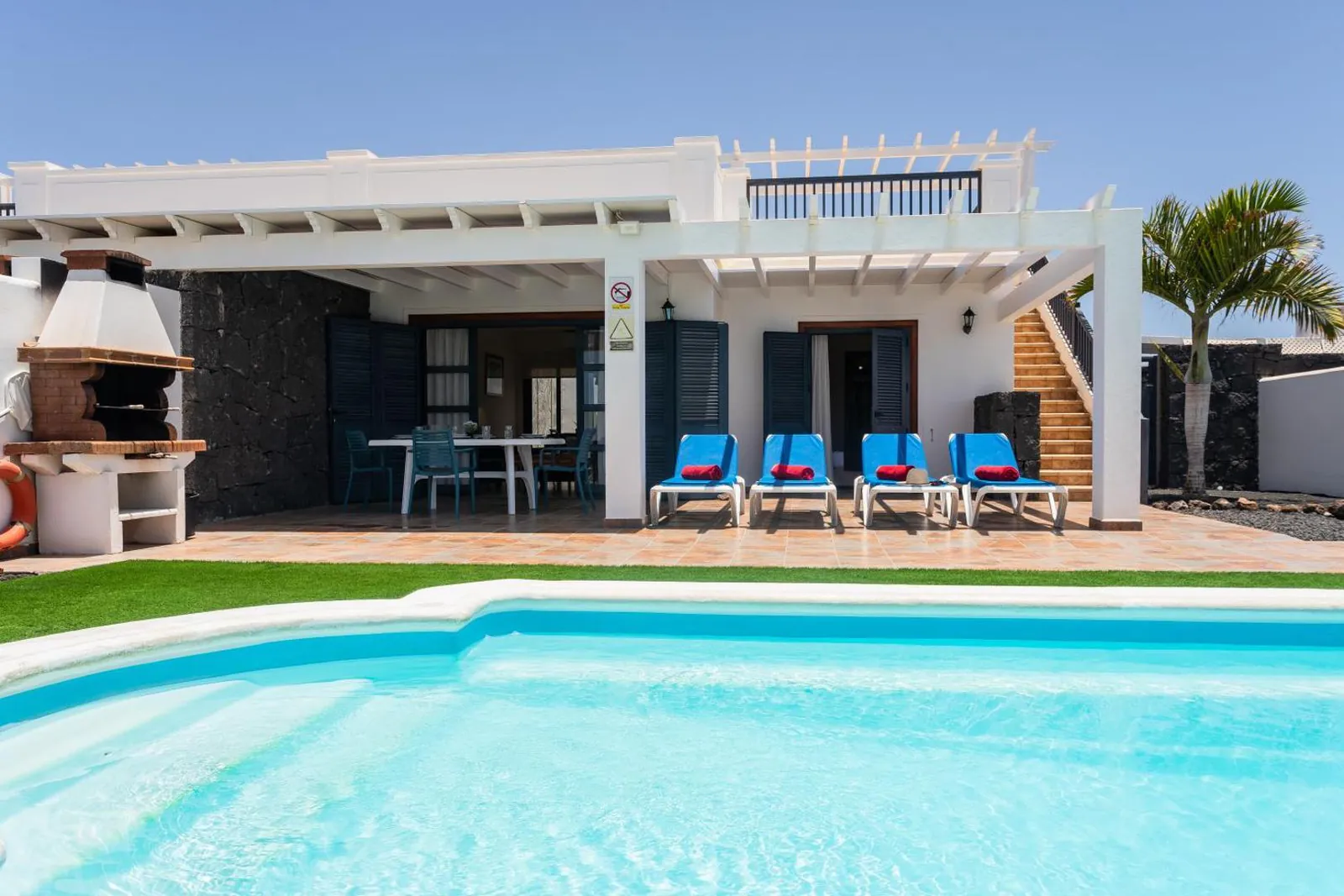Close view of the private pool with loungers on the terrace and the villa behind
