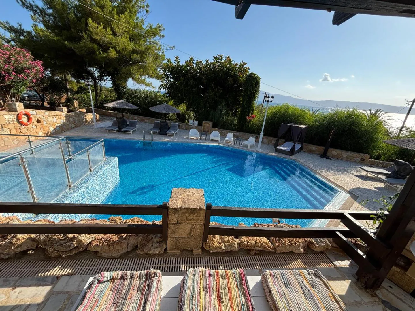 Outdoor pool with a stone wall and the sea beyond the garden at Villas Vista Del Mar