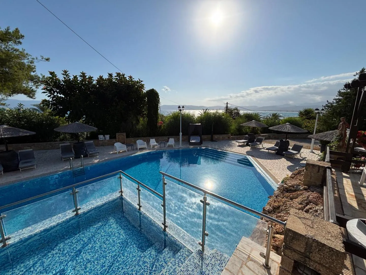 Pool with a glass-fenced deck and views across the bay to the mountains