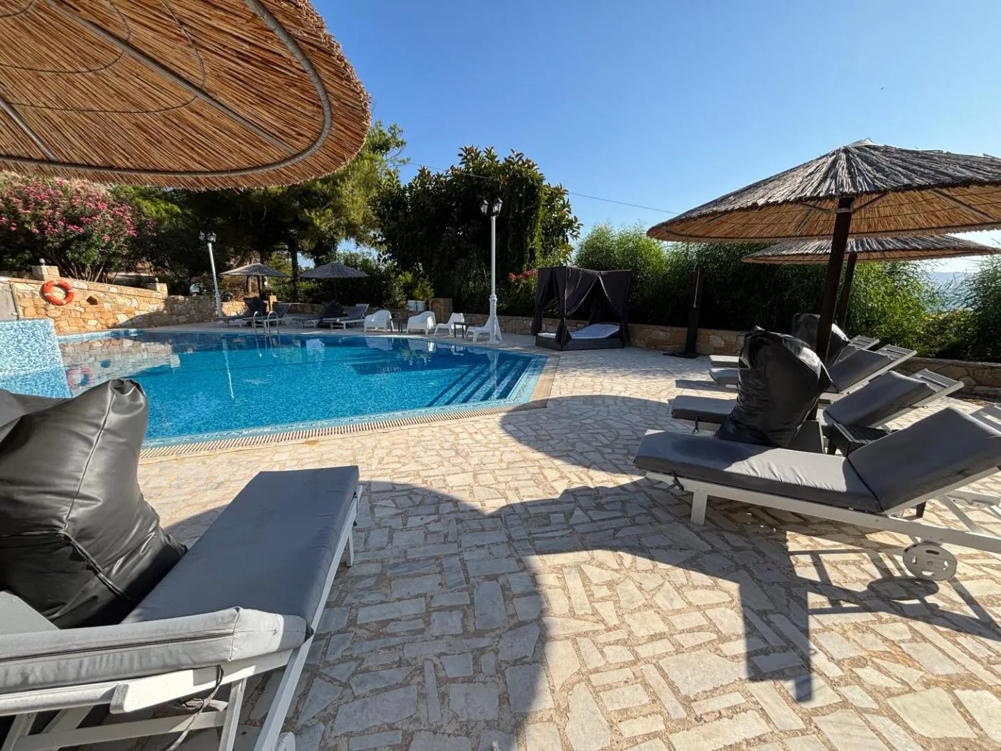 Loungers, beanbags and thatched parasols on the stone pool terrace