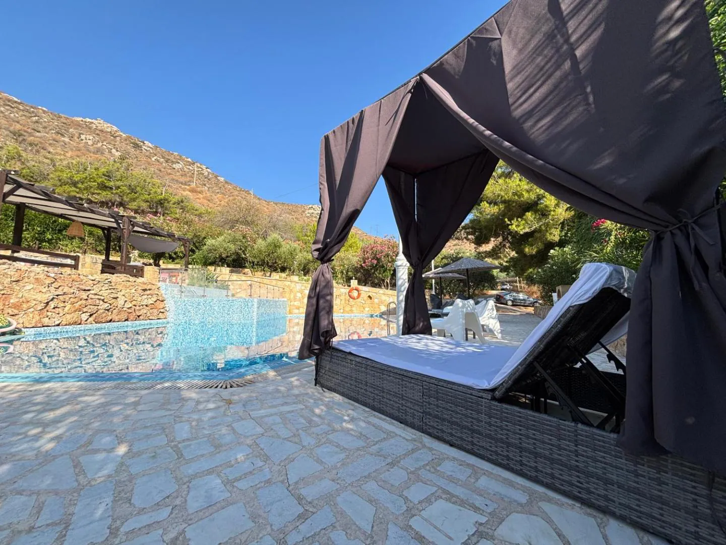 Canopied daybed on the pool terrace below the hillside