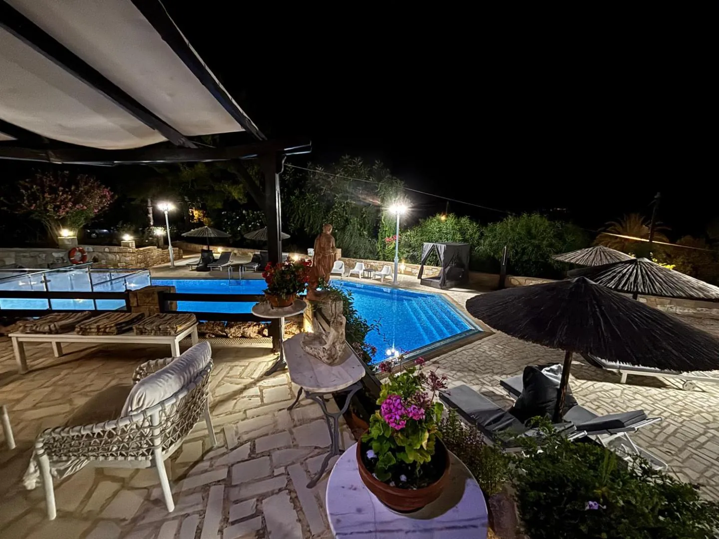 Pool terrace lit up at night with loungers and parasols