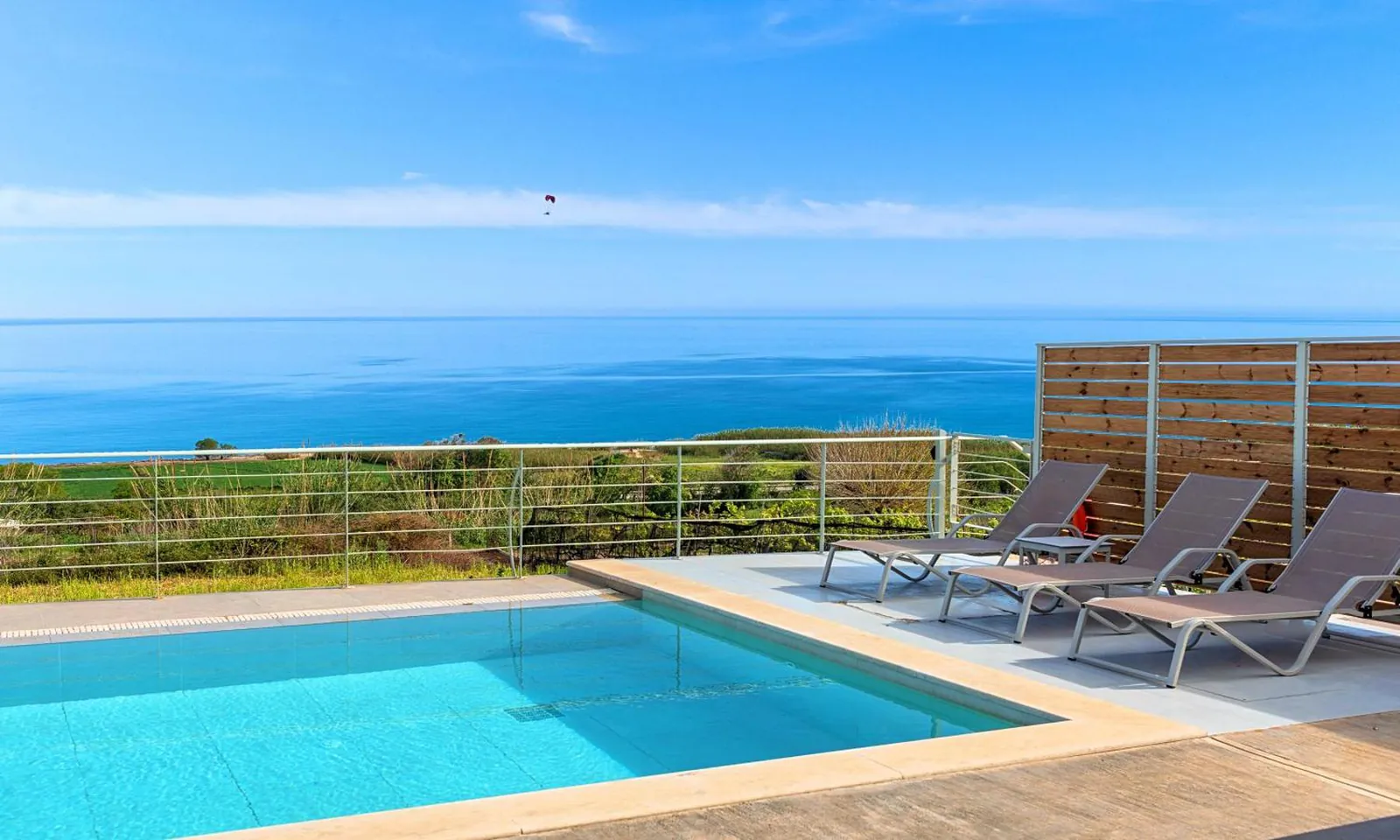 Heated private pool at Vista Mare Villas with loungers and the sea beyond the railing