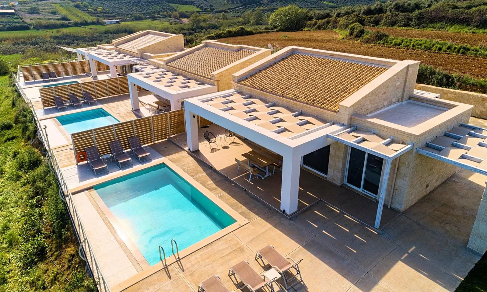 Aerial view of two stone villas, each with its own pool