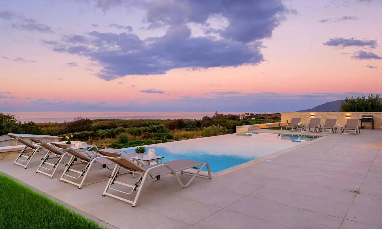 The pool deck at dusk with the sea and the coastline beyond