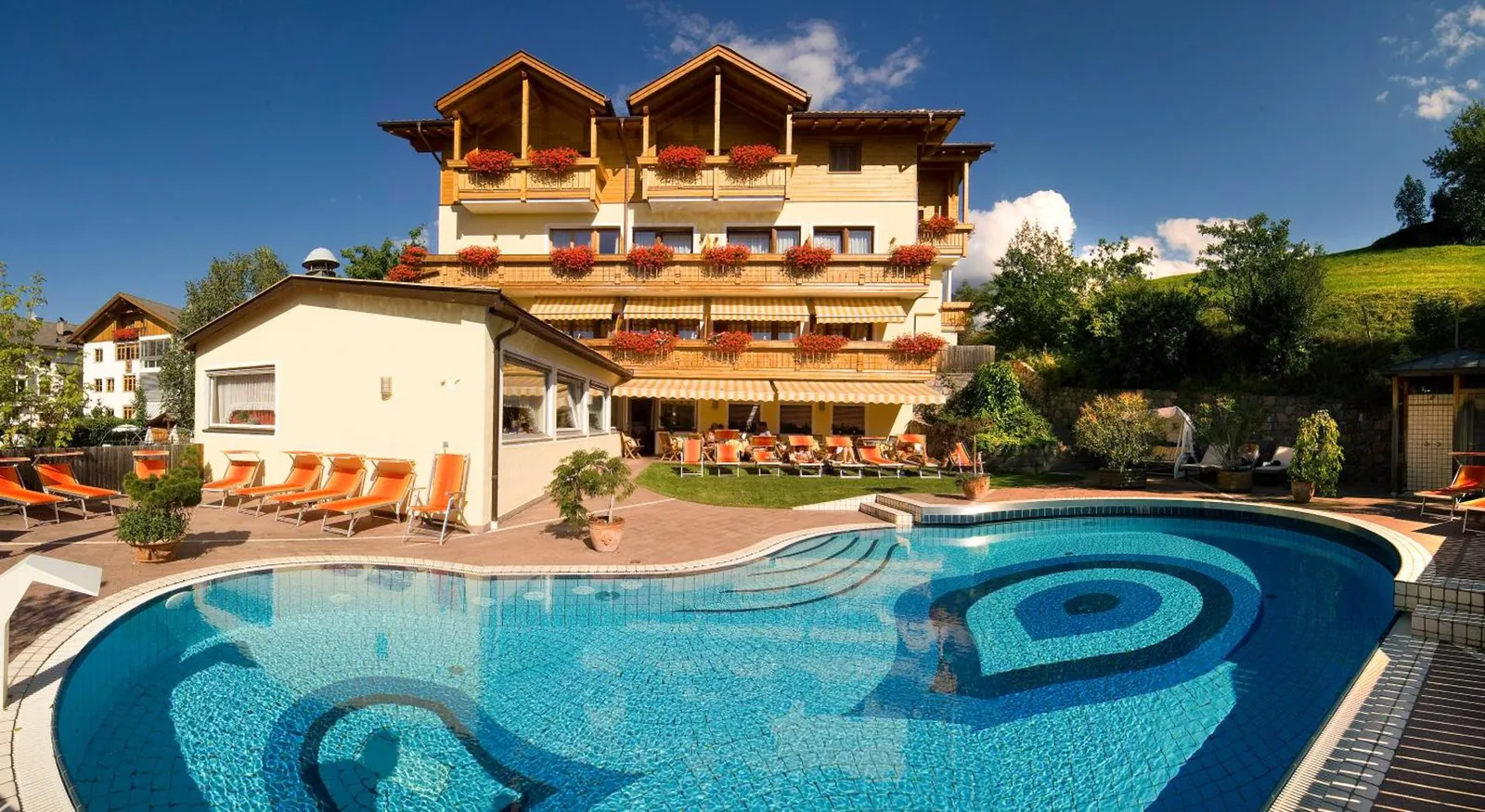 Outdoor pool with a blue spiral tile pattern in front of Wanderhotel Teiserhof