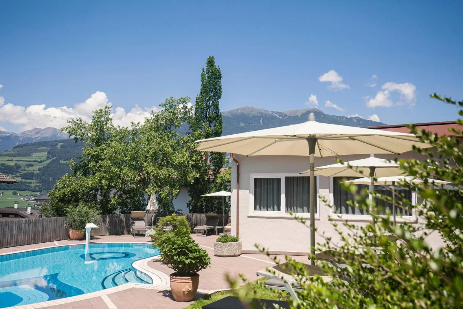 Pool with a parasol and mountain views over a garden wall